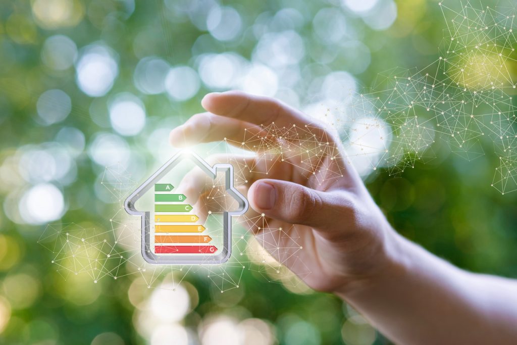 Hand shows a model energy efficient house on blurred background.